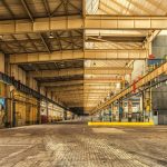 Interior amplo de um armazém industrial com estruturas metálicas, teto alto e espaço para operações.