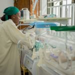 Médico atende recém-nascidos em incubadoras em uma unidade hospitalar neonatal.